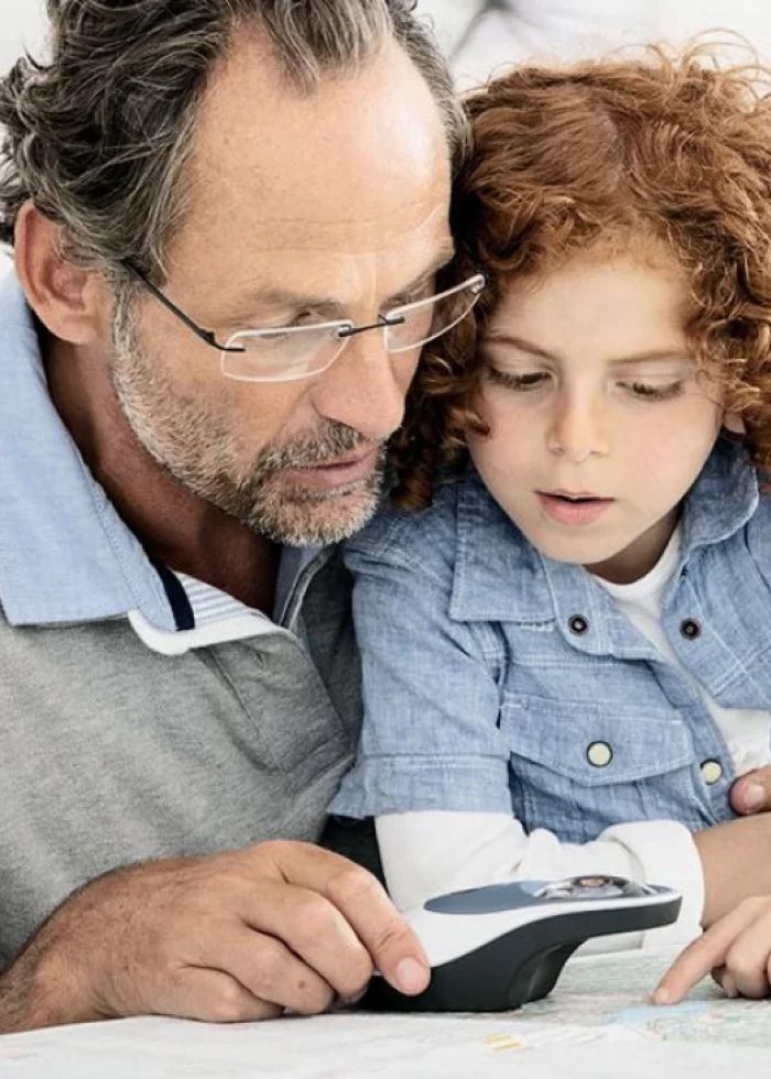 Hombre y niño usando dispositivo de aumento visual para leer